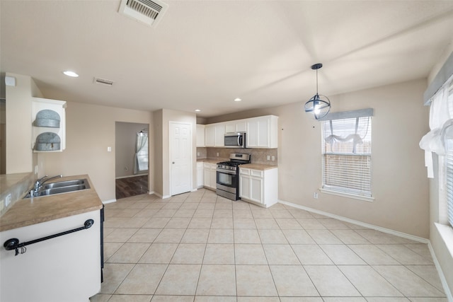 kitchen featuring stainless steel appliances, pendant lighting, decorative backsplash, sink, and white cabinetry