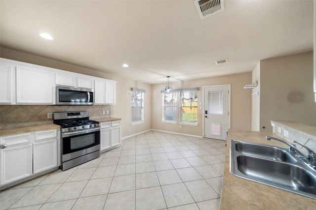 kitchen featuring pendant lighting, white cabinets, sink, and stainless steel appliances