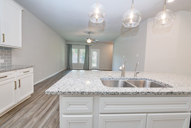 kitchen featuring a center island with sink, hardwood / wood-style floors, sink, ceiling fan, and backsplash