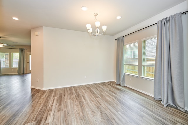 spare room with ceiling fan with notable chandelier and light hardwood / wood-style flooring