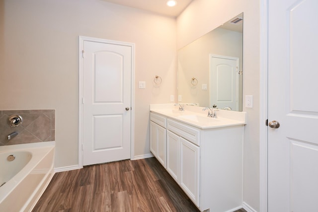 9291 Inland Leather Ln, Conroe, TX 77385 - bathroom featuring a garden tub, wood finished floors, double vanity, and baseboards