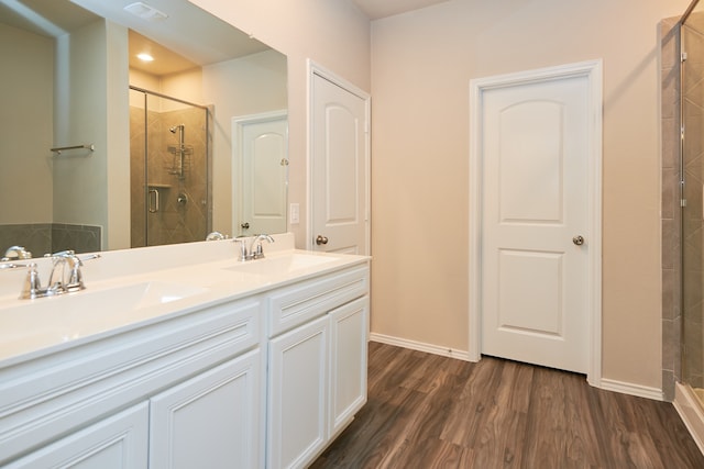 bathroom with hardwood / wood-style floors, vanity, and a shower with door