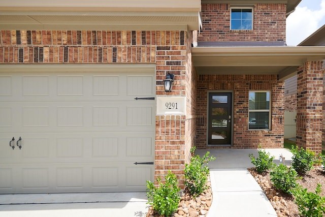 9291 Inland Leather Ln, Conroe, TX 77385 - view of exterior entry with brick siding, concrete driveway, and a garage