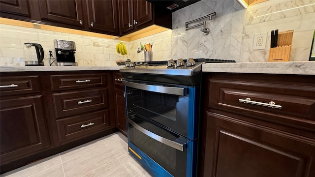 kitchen featuring double oven range, light tile patterned floors, and decorative backsplash