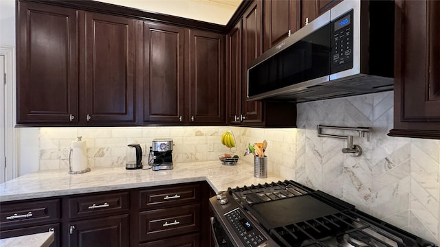 kitchen with appliances with stainless steel finishes, light stone countertops, dark brown cabinets, and backsplash