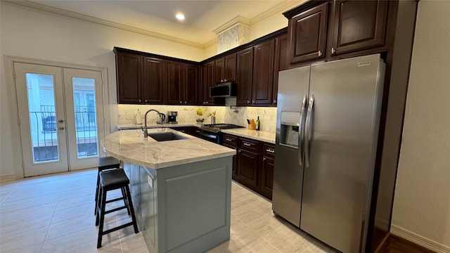 kitchen with sink, a breakfast bar area, stainless steel appliances, an island with sink, and decorative backsplash