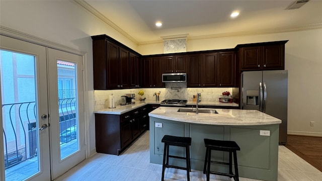 kitchen with sink, a breakfast bar, stainless steel appliances, an island with sink, and french doors