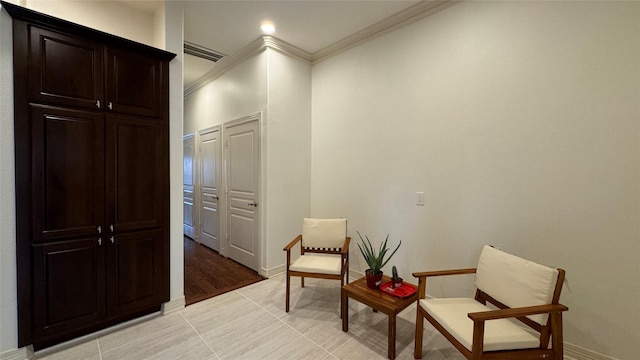 sitting room with crown molding and light tile patterned floors