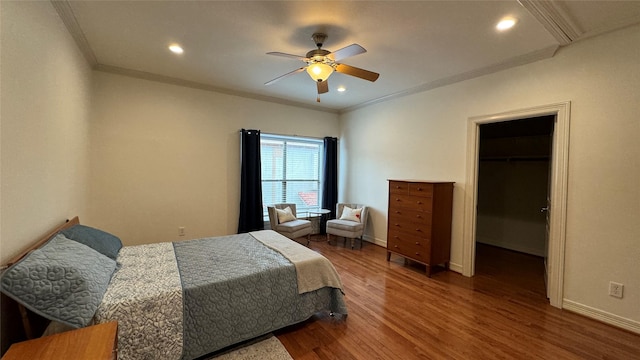 bedroom featuring hardwood / wood-style flooring, ornamental molding, a walk in closet, and ceiling fan