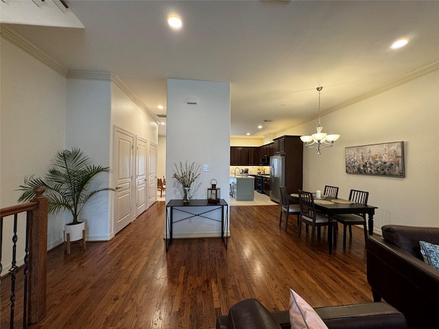 living room featuring dark wood-type flooring, ornamental molding, and a notable chandelier