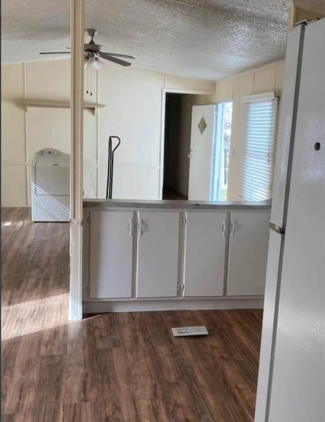 kitchen with ceiling fan, a textured ceiling, washer / dryer, dark wood-type flooring, and white refrigerator