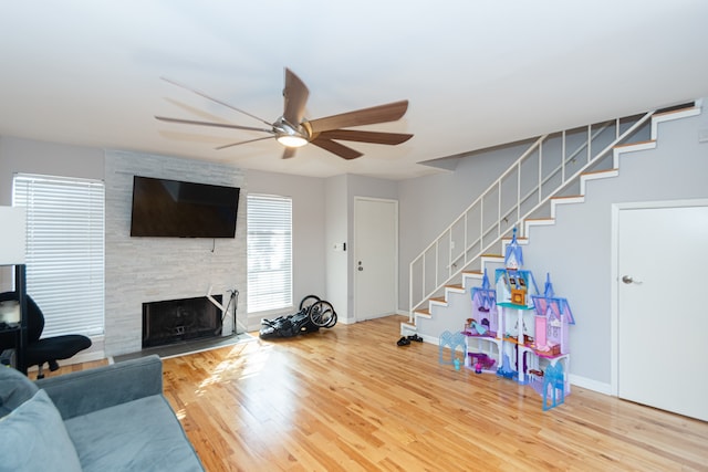 living room featuring a fireplace, hardwood / wood-style floors, and ceiling fan