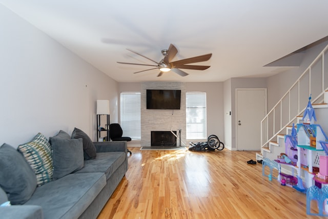 living room featuring hardwood / wood-style flooring, ceiling fan, and a fireplace