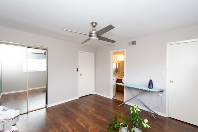 unfurnished bedroom featuring ceiling fan, dark hardwood / wood-style flooring, connected bathroom, and a closet