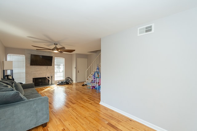 living room with a large fireplace, ceiling fan, and light hardwood / wood-style flooring