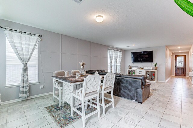 tiled dining space with a textured ceiling