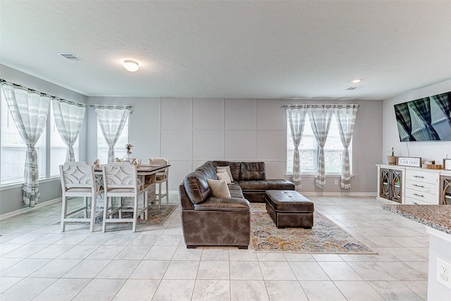 living room with light tile patterned floors, a textured ceiling, and plenty of natural light