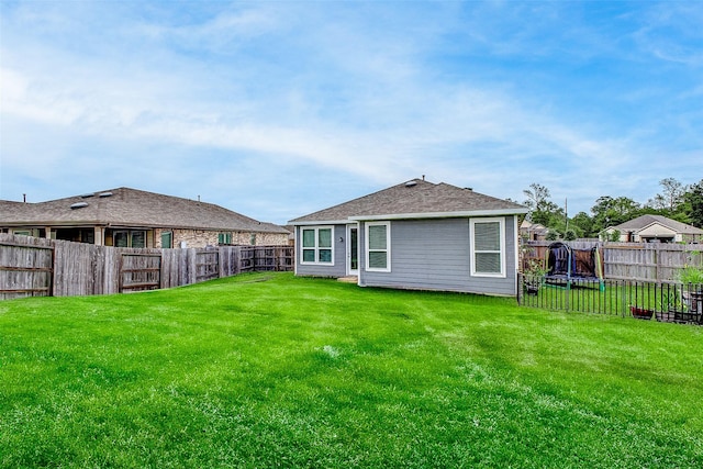 rear view of house with a trampoline and a yard