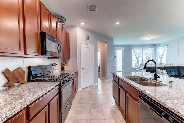 kitchen featuring dishwasher, black range with gas stovetop, sink, light tile patterned floors, and light stone counters