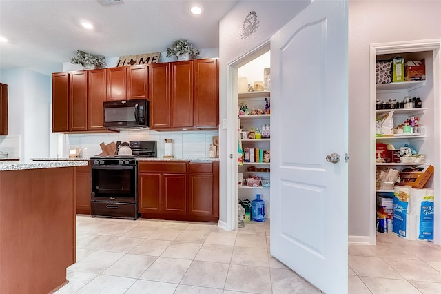 kitchen with light stone countertops, light tile patterned floors, and black appliances