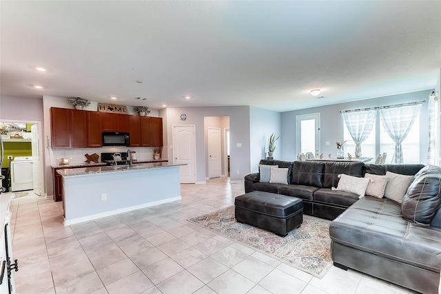 living room featuring sink, light tile patterned floors, and washer / dryer