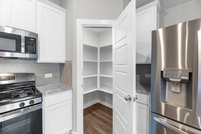 kitchen with wood-type flooring, white cabinets, tasteful backsplash, light stone countertops, and appliances with stainless steel finishes