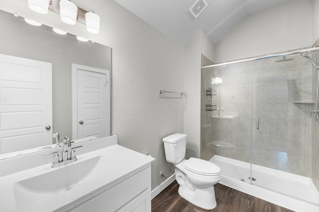 bathroom with wood-type flooring, a shower with door, vanity, vaulted ceiling, and toilet