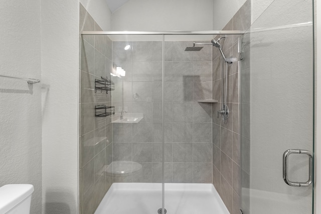 bathroom featuring toilet and a shower with door