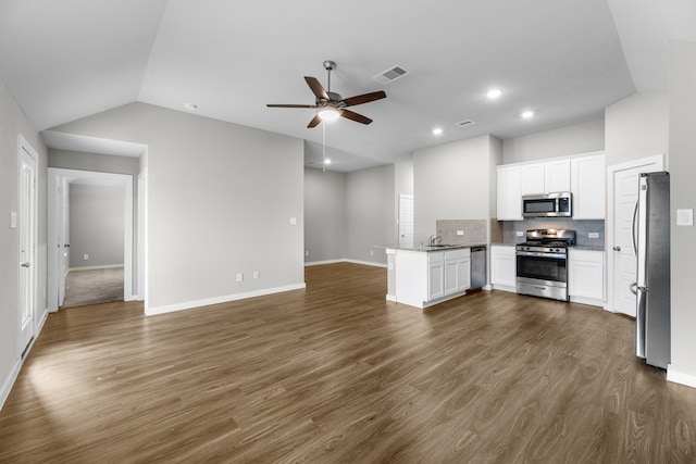 kitchen featuring appliances with stainless steel finishes, white cabinets, dark wood-type flooring, kitchen peninsula, and lofted ceiling