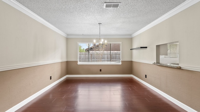 unfurnished dining area featuring a textured ceiling, dark hardwood / wood-style flooring, a chandelier, and crown molding