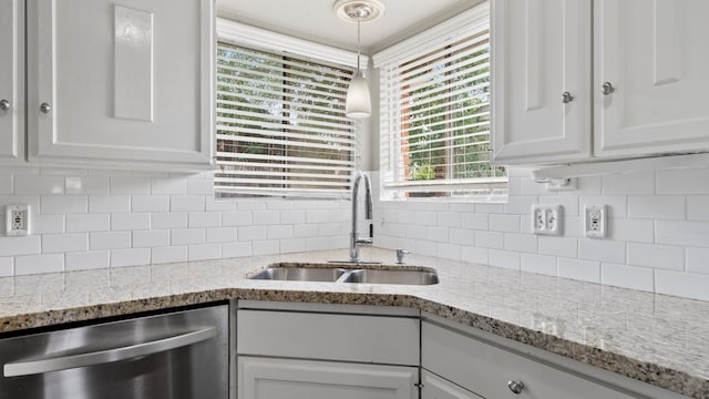 kitchen with tasteful backsplash, decorative light fixtures, sink, white cabinets, and dishwasher