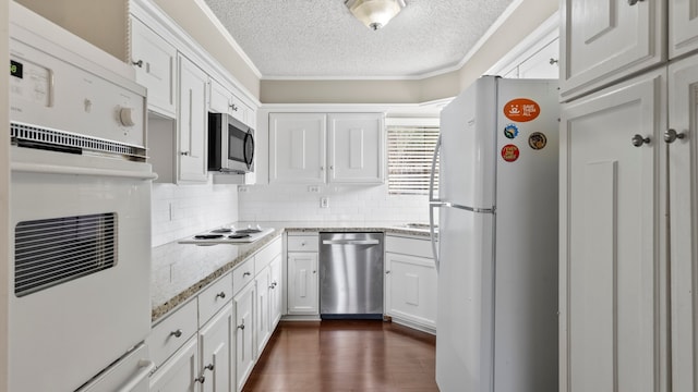 kitchen with stainless steel appliances, a textured ceiling, dark hardwood / wood-style floors, light stone countertops, and white cabinets