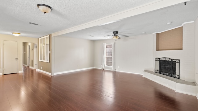 unfurnished living room featuring dark wood-type flooring, a textured ceiling, and a brick fireplace