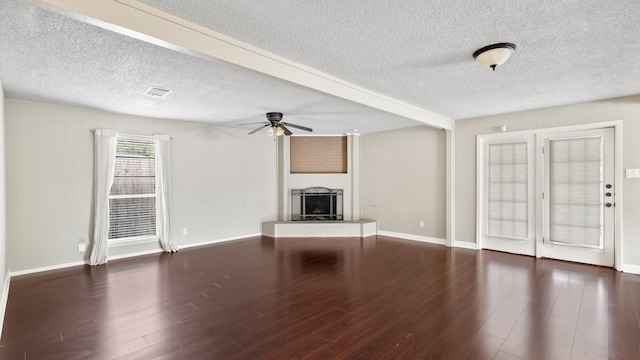 unfurnished living room with a textured ceiling, dark hardwood / wood-style floors, and a brick fireplace