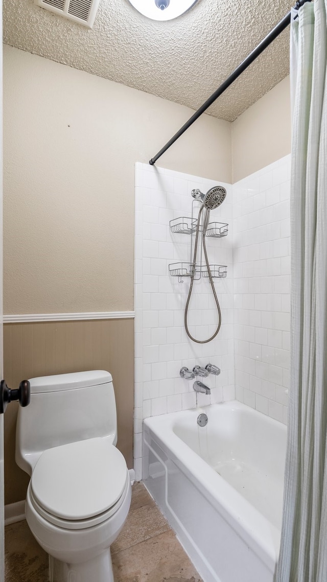 bathroom featuring tile patterned flooring, a textured ceiling, toilet, and shower / bath combination with curtain