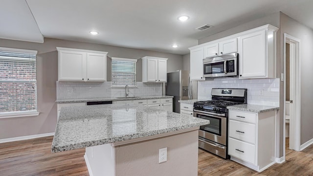 kitchen with a kitchen island, sink, white cabinetry, light hardwood / wood-style flooring, and appliances with stainless steel finishes