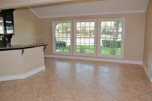 interior space featuring light tile patterned flooring, a healthy amount of sunlight, lofted ceiling, and crown molding