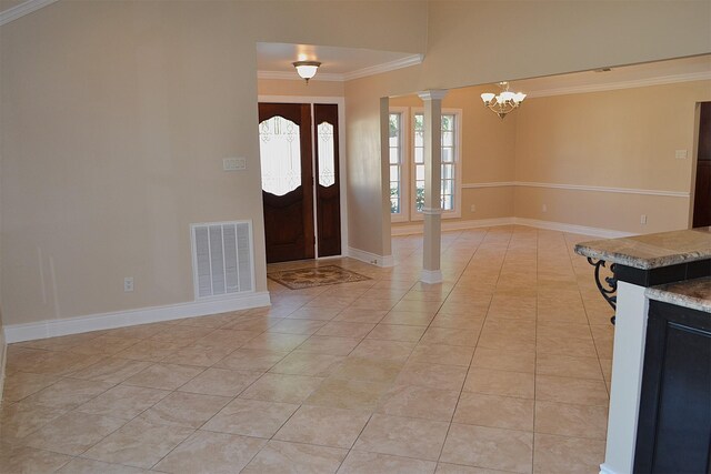 foyer entrance featuring ornate columns, ornamental molding, light tile patterned flooring, and an inviting chandelier