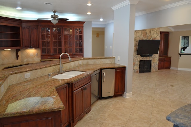 kitchen with light tile patterned flooring, sink, ornamental molding, light stone countertops, and a fireplace