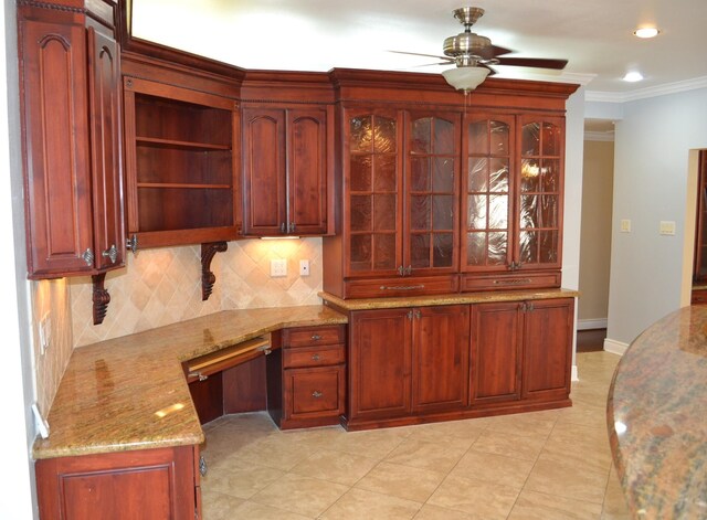 kitchen featuring tasteful backsplash, built in desk, ornamental molding, light stone countertops, and ceiling fan