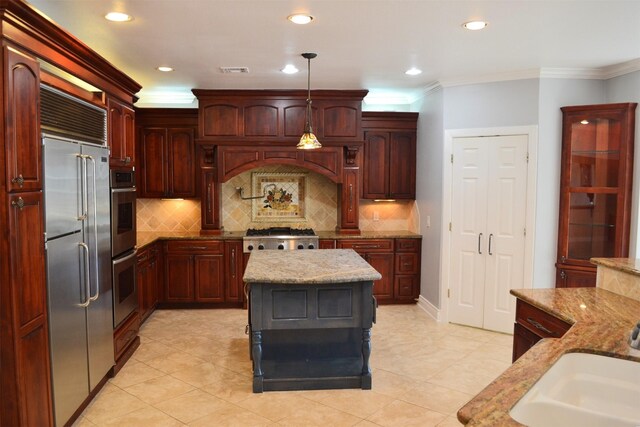 kitchen with a kitchen island, appliances with stainless steel finishes, light stone counters, and hanging light fixtures