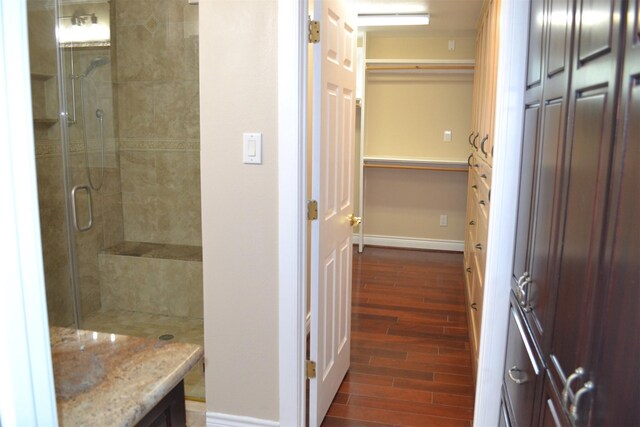 bathroom with wood-type flooring, vanity, and a shower with door