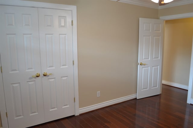 unfurnished bedroom featuring a closet, dark hardwood / wood-style floors, and crown molding