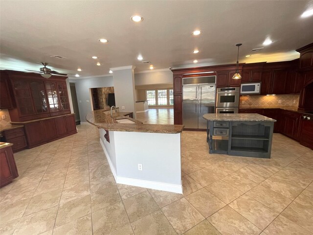 kitchen with stainless steel appliances, sink, ceiling fan, hanging light fixtures, and a center island