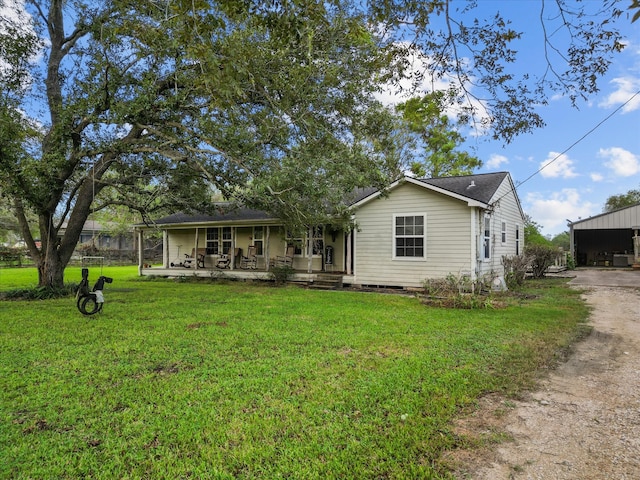 rear view of house with covered porch and a yard