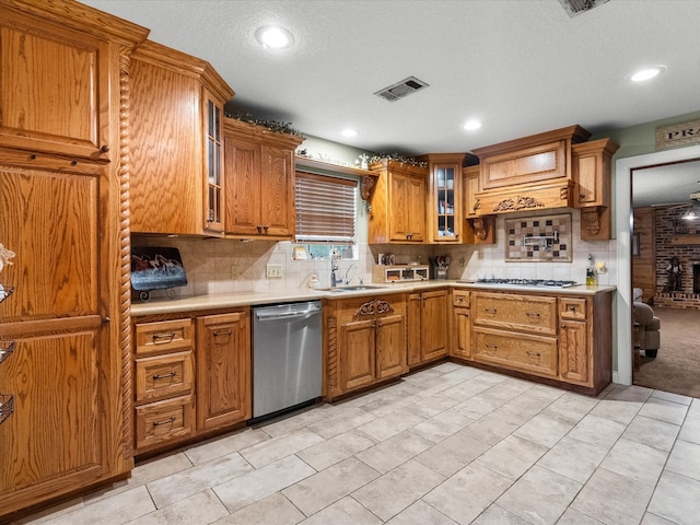 kitchen featuring sink, a brick fireplace, light tile patterned floors, a textured ceiling, and appliances with stainless steel finishes