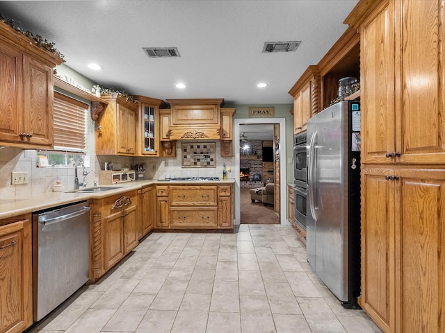 kitchen with sink, tasteful backsplash, a textured ceiling, light tile patterned floors, and appliances with stainless steel finishes