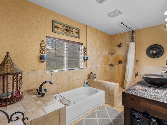 bathroom with tile patterned floors, vanity, independent shower and bath, and tile walls