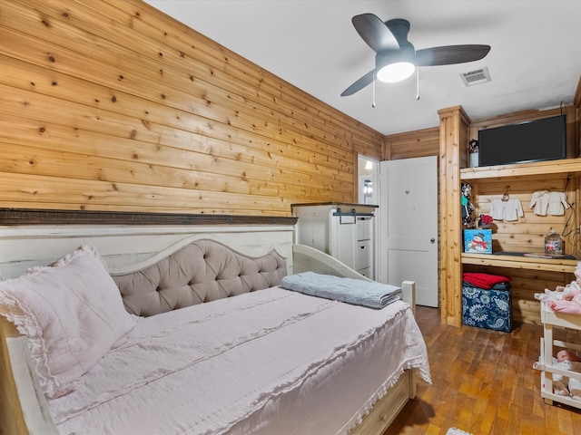 bedroom with hardwood / wood-style floors, ceiling fan, and wood walls