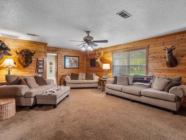 living room with wood walls, carpet floors, and a textured ceiling